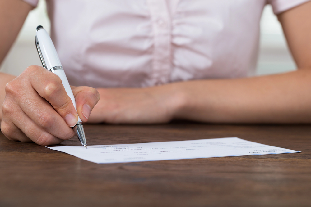 Hands signing a check