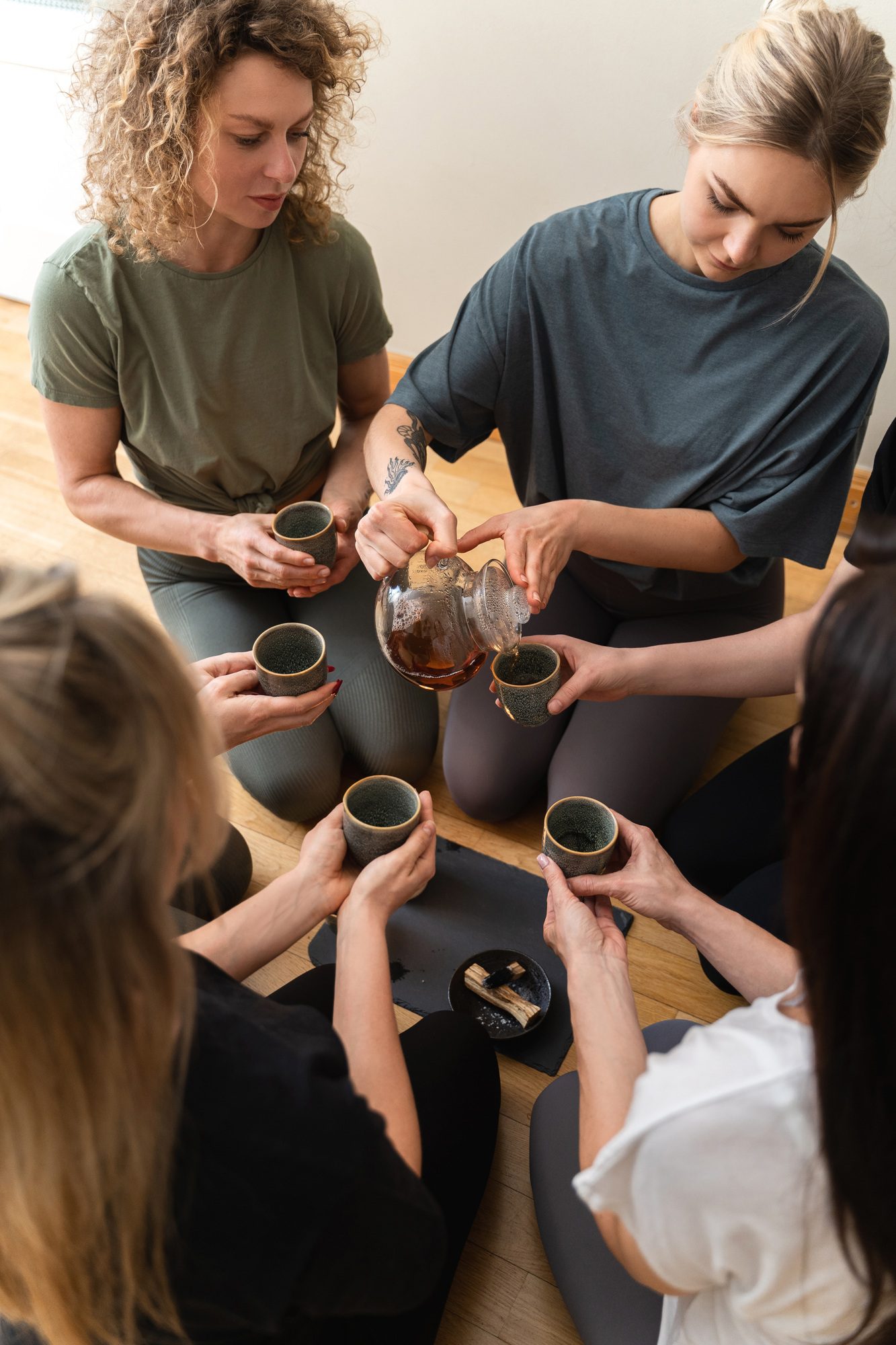 Woman pouring tea to her friends during tea ceremony.